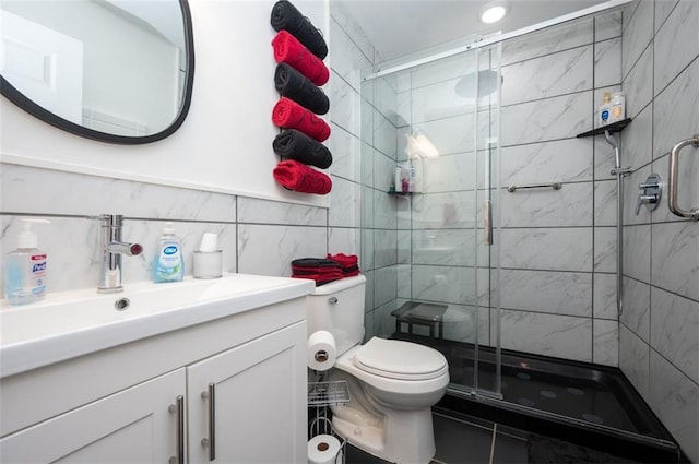 full bath featuring tile walls, toilet, a shower stall, and vanity