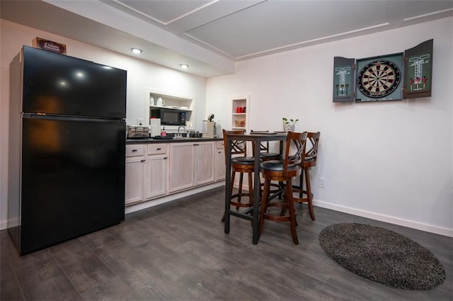 kitchen with baseboards, dark countertops, dark wood-style floors, black appliances, and a sink