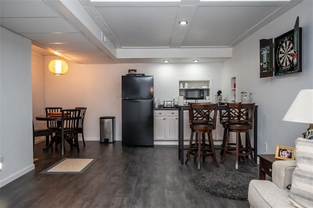 kitchen featuring dark wood-style floors, freestanding refrigerator, dark countertops, and baseboards