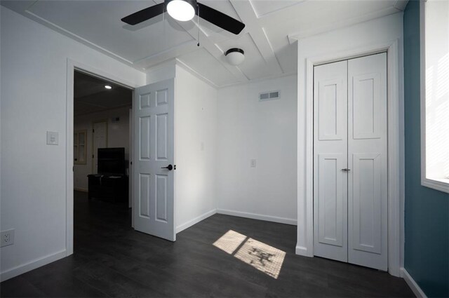 unfurnished bedroom with baseboards, visible vents, dark wood finished floors, ceiling fan, and a closet