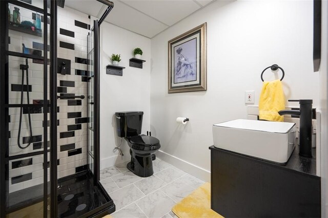 bathroom featuring toilet, marble finish floor, a shower stall, and a sink