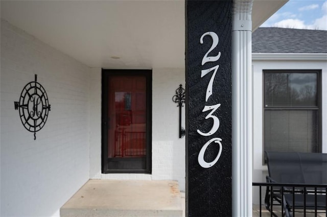 doorway to property with roof with shingles