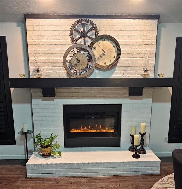 details with a textured ceiling, a brick fireplace, wood finished floors, and baseboards