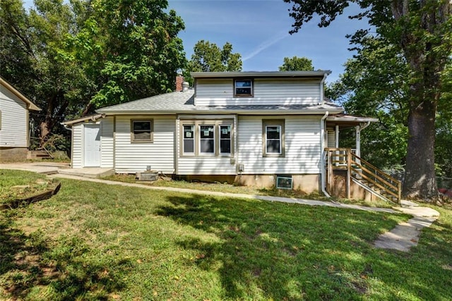 rear view of property featuring a chimney and a lawn