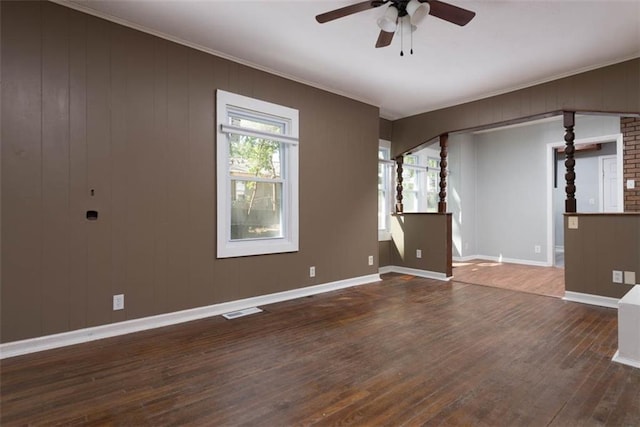 empty room featuring visible vents, ornamental molding, dark wood-style floors, and a wealth of natural light