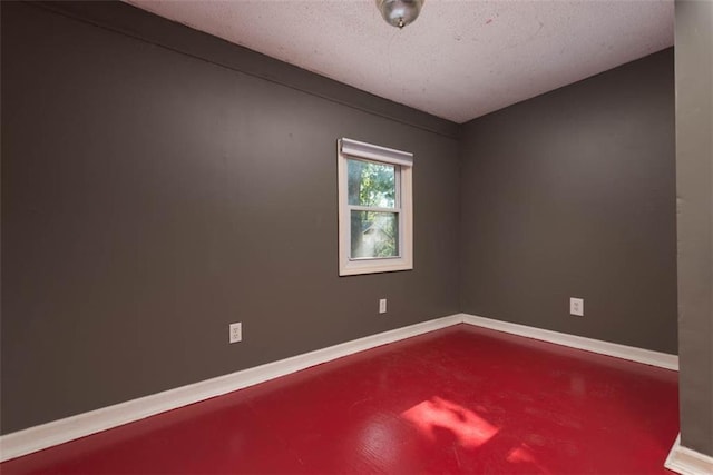 spare room with concrete flooring, a textured ceiling, and baseboards