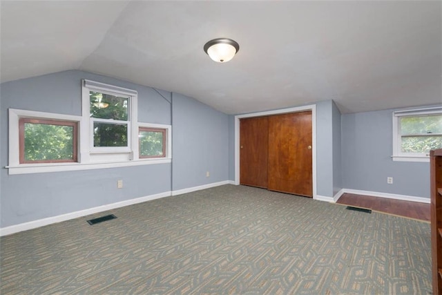 additional living space with lofted ceiling, visible vents, and baseboards