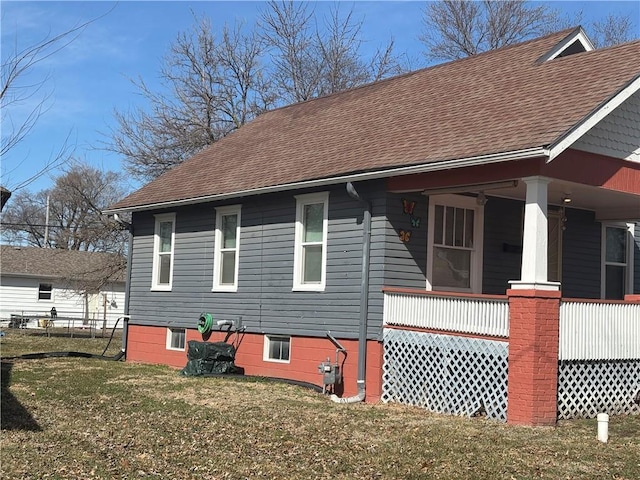 view of side of property featuring a yard, a porch, roof with shingles, and fence