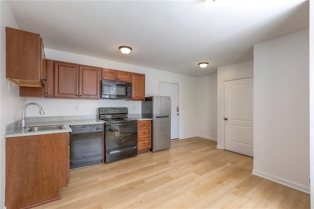 kitchen featuring light countertops, brown cabinets, a sink, and black appliances