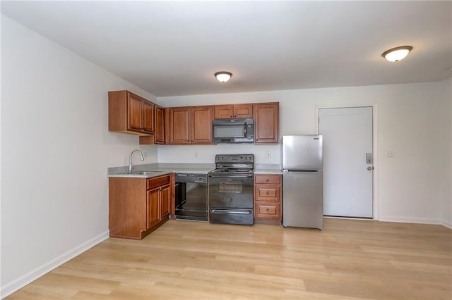 kitchen featuring black appliances, light countertops, light wood-style flooring, and brown cabinets