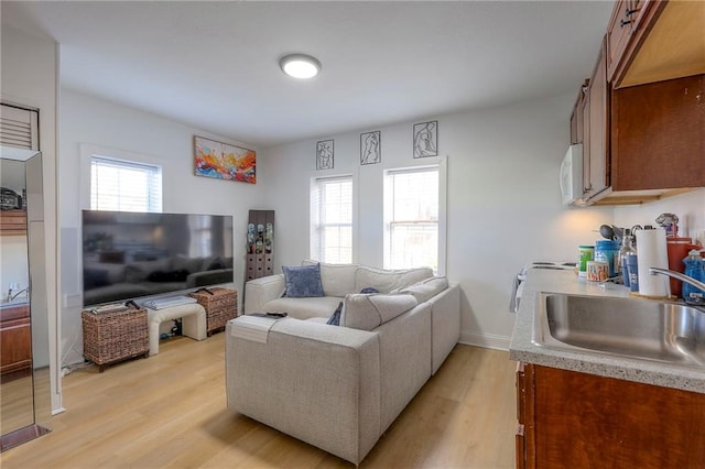 living area featuring plenty of natural light, light wood-type flooring, and baseboards