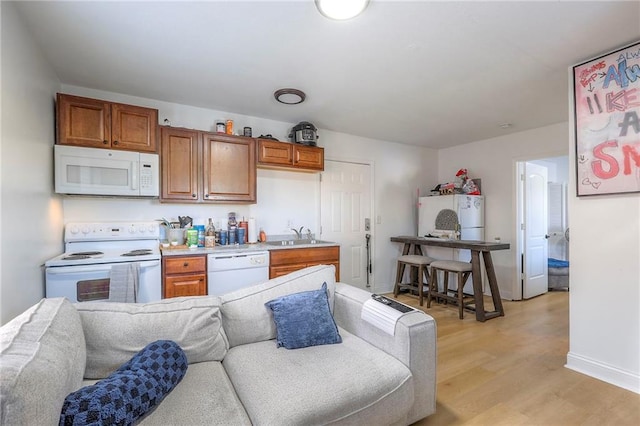 kitchen with light wood finished floors, light countertops, brown cabinetry, open floor plan, and white appliances