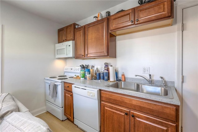 kitchen featuring brown cabinetry, white appliances, light countertops, and a sink