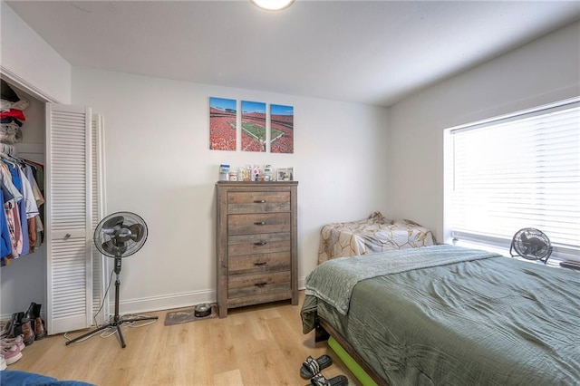 bedroom with light wood-type flooring, a closet, and baseboards