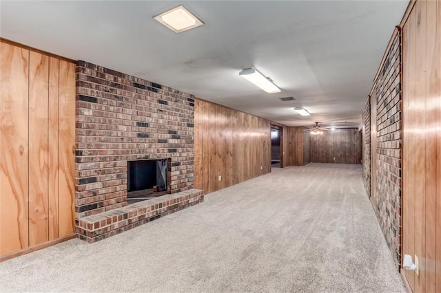 below grade area with ceiling fan, carpet, a brick fireplace, and wood walls