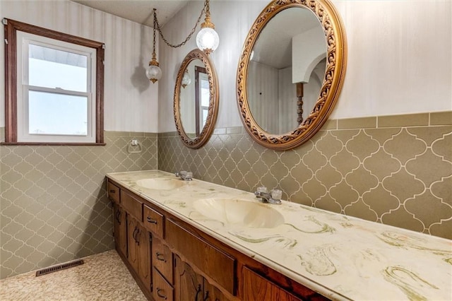 bathroom featuring double vanity, wainscoting, visible vents, and a sink