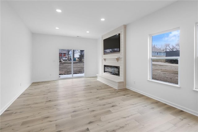 unfurnished living room featuring light wood finished floors, recessed lighting, a large fireplace, and baseboards