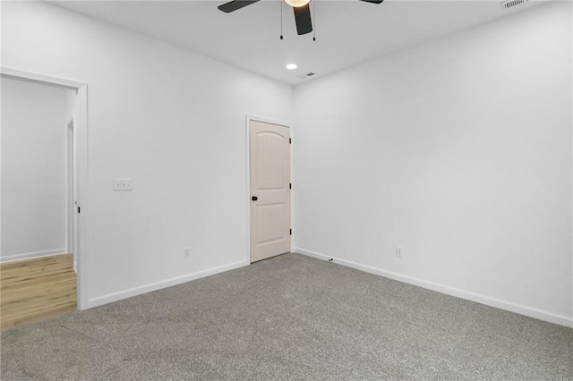 unfurnished room with carpet, visible vents, and baseboards