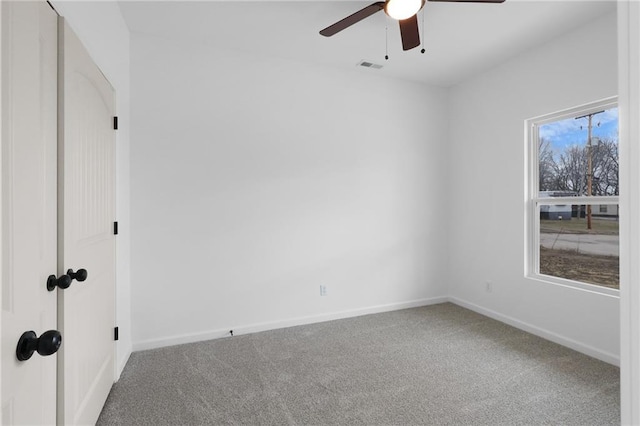 carpeted empty room with visible vents, baseboards, and a ceiling fan