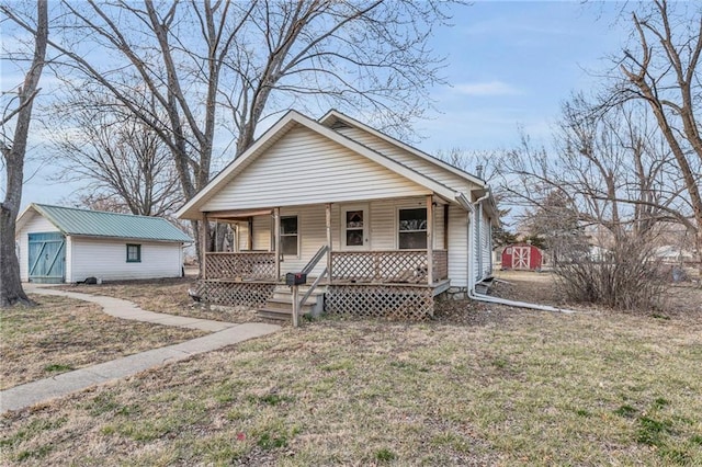 bungalow-style home featuring a storage shed, a porch, a front lawn, and an outdoor structure