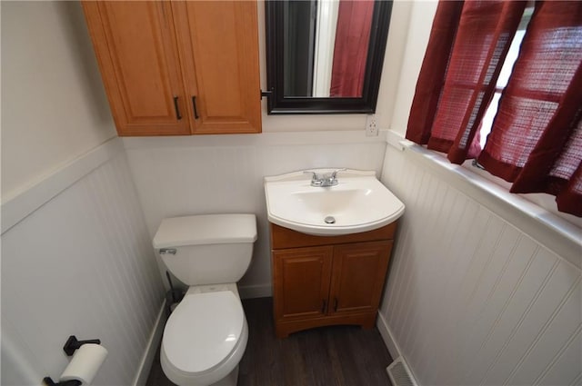 bathroom with visible vents, wainscoting, toilet, wood finished floors, and vanity