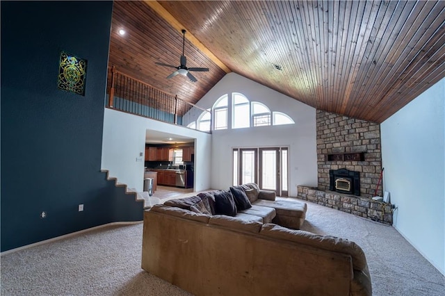 carpeted living area featuring high vaulted ceiling, a ceiling fan, stairs, a fireplace, and wooden ceiling