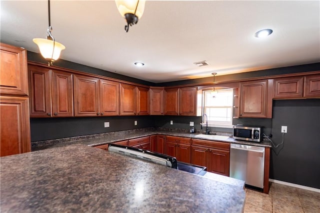 kitchen with dark countertops, a sink, brown cabinetry, and appliances with stainless steel finishes