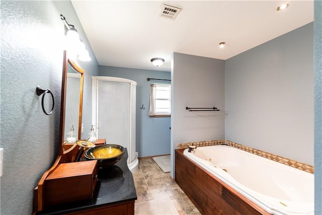 bathroom with a shower stall, a jetted tub, visible vents, vanity, and baseboards
