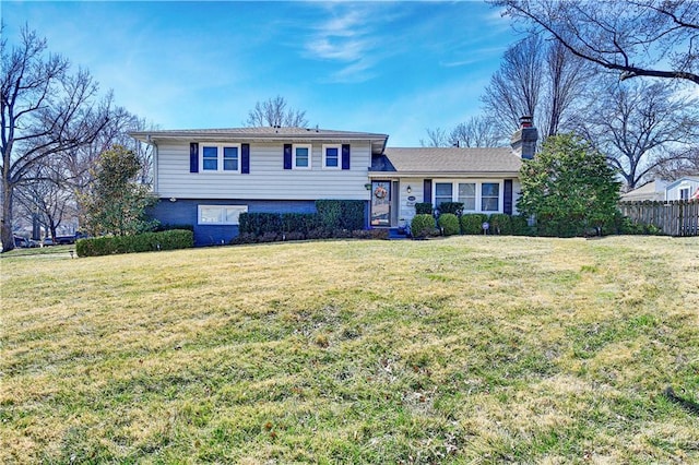 tri-level home with a chimney, a front yard, and fence