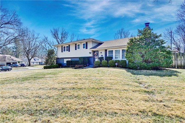 tri-level home with a front lawn and fence