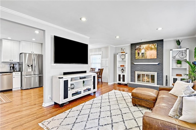 living room featuring recessed lighting, a brick fireplace, light wood-type flooring, and ornamental molding