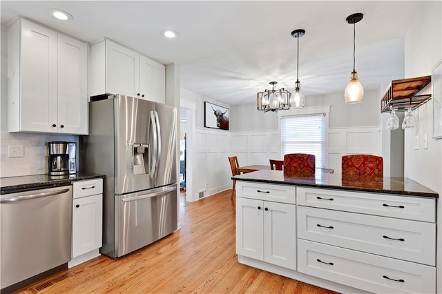 kitchen with stainless steel appliances, a notable chandelier, white cabinets, and light wood-style flooring