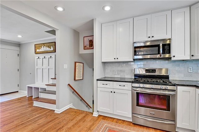 kitchen with white cabinetry, tasteful backsplash, light wood finished floors, and stainless steel appliances