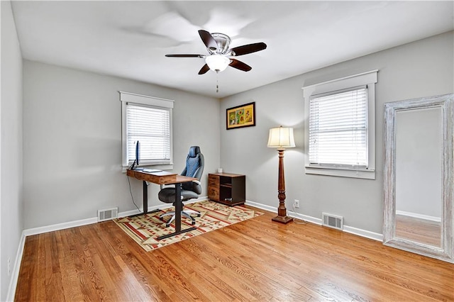 office space with visible vents, baseboards, a ceiling fan, and wood finished floors