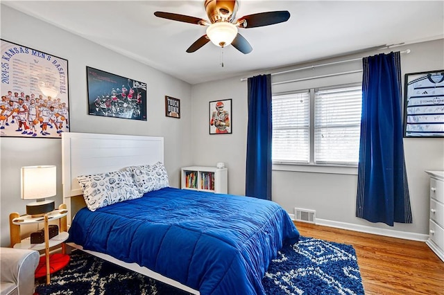 bedroom featuring visible vents, baseboards, wood finished floors, and a ceiling fan