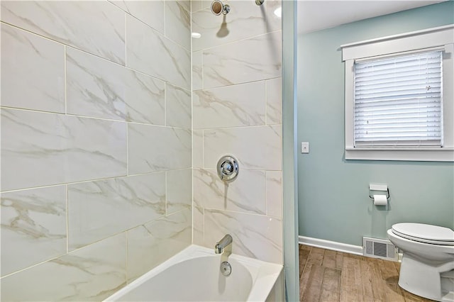 full bathroom featuring wood finished floors, visible vents, baseboards, shower / bathing tub combination, and toilet