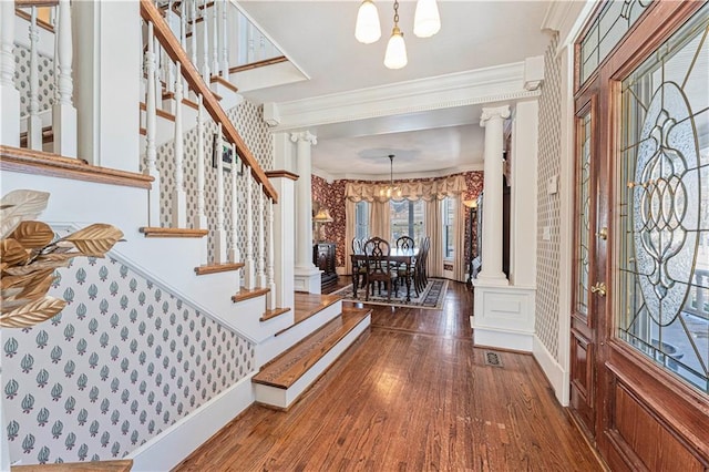 entrance foyer featuring stairway, wood finished floors, baseboards, decorative columns, and ornamental molding