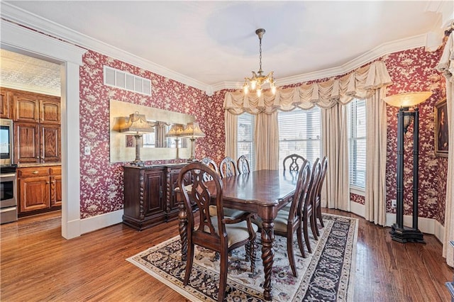 dining space featuring visible vents, wallpapered walls, baseboards, a chandelier, and wood finished floors