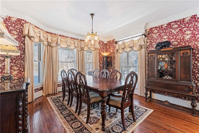 dining area featuring wood finished floors, a chandelier, ornamental molding, and wallpapered walls