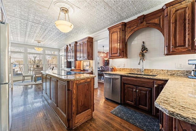 kitchen featuring dark wood-type flooring, appliances with stainless steel finishes, an ornate ceiling, and a sink