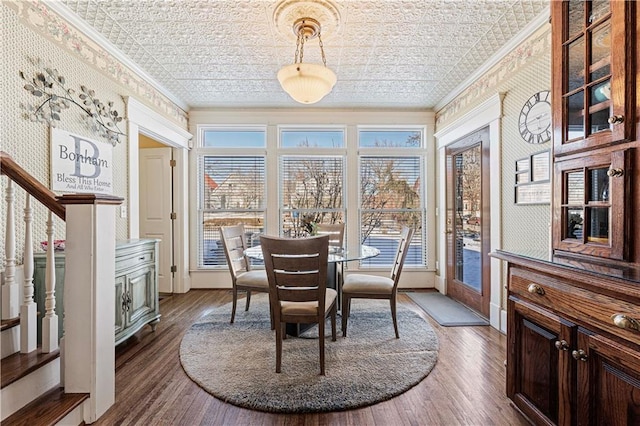 dining space with dark wood finished floors, crown molding, and an ornate ceiling