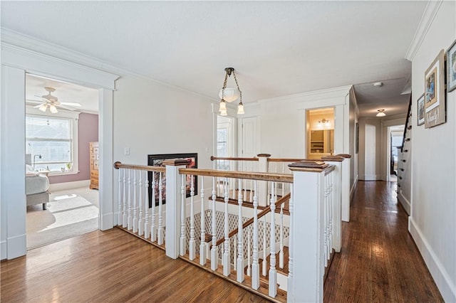 hallway with baseboards, an upstairs landing, dark wood finished floors, and crown molding