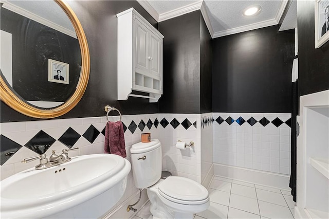 full bathroom with tile patterned floors, toilet, ornamental molding, a sink, and a textured ceiling