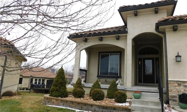 entrance to property featuring a tiled roof and stucco siding