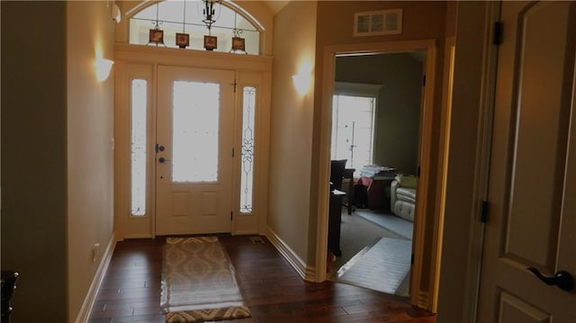 foyer with a wealth of natural light, visible vents, dark wood-type flooring, and baseboards