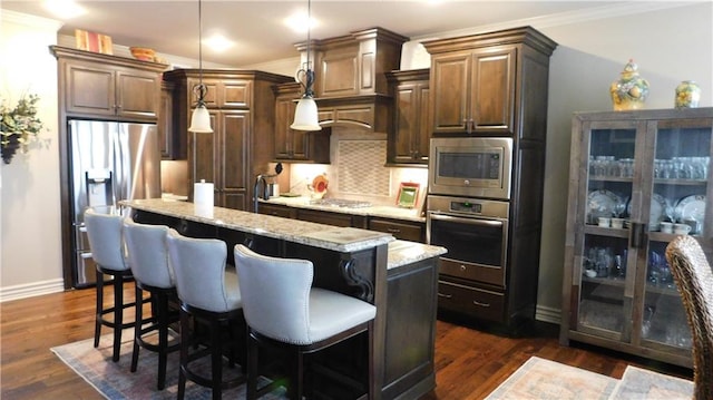 kitchen featuring dark wood-style floors, a kitchen island, ornamental molding, stainless steel appliances, and tasteful backsplash