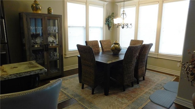 dining area featuring baseboards, an inviting chandelier, and wood finished floors