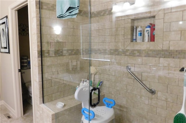 bathroom featuring tiled shower and toilet