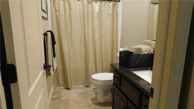 full bathroom featuring stone finish floor, toilet, vanity, and a shower with curtain