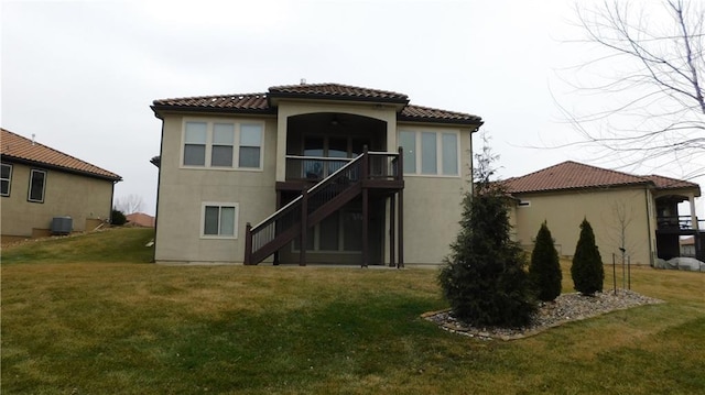 back of property with central air condition unit, a lawn, and stairway